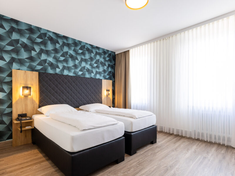 Modernes Doppel- oder Zweibettzimmer mit zwei Einzelbetten auf Laminat