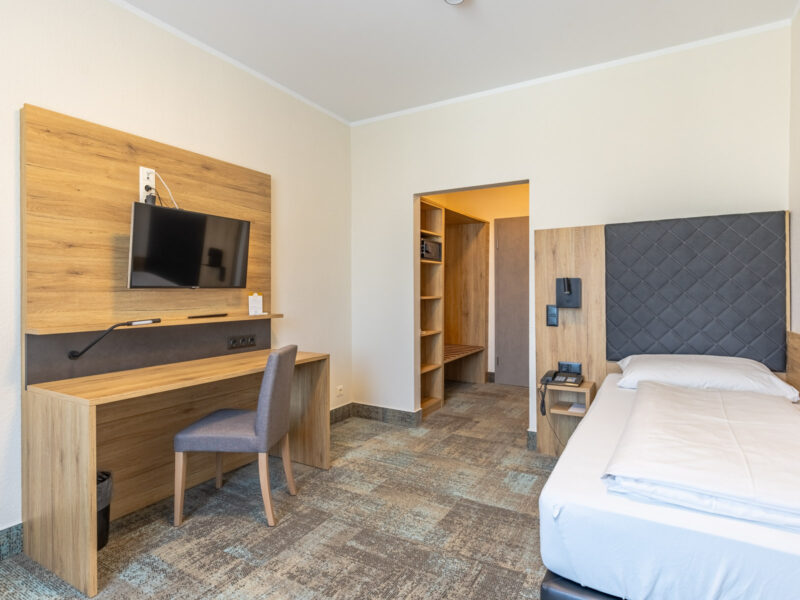 Modernes Einzelzimmer mit Schreibtisch, Schrank und TV