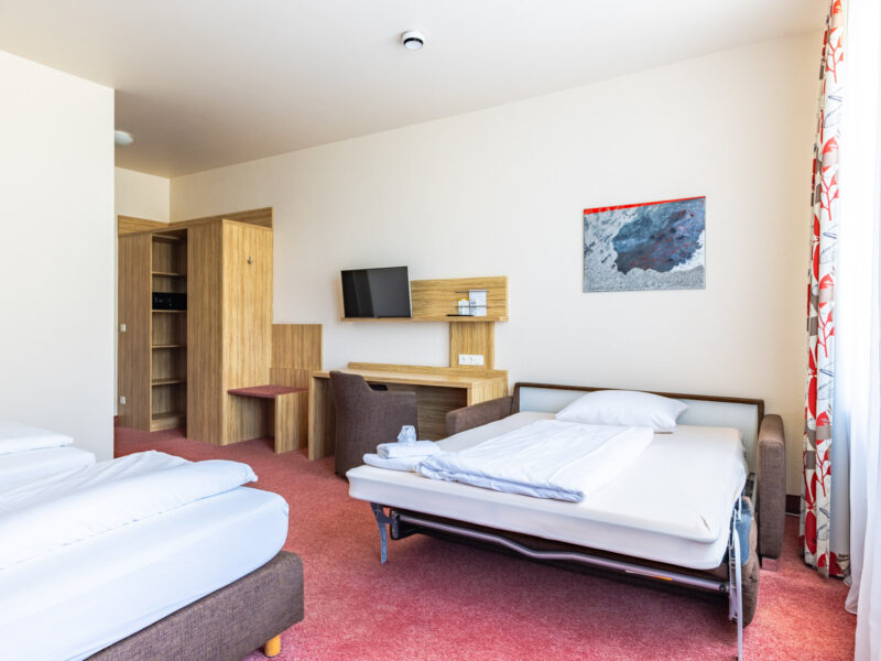 Dreibettzimmer mit ausgezogener Schlafcouch