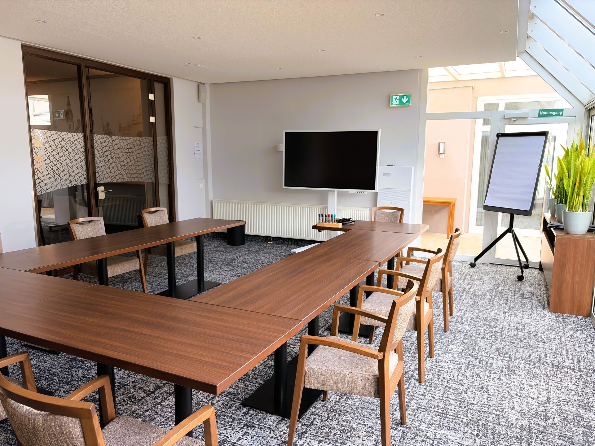 Moderner Tagungsraum mit viel Tageslicht, Bestuhlung, Smart-TV und Flipchart